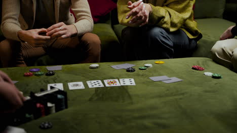 Camera-Focuses-On-The-Hands-Of-A-Group-Of-Friends-Who-Take-Playing-Cards-And-Poker-Chips-On-The-Table