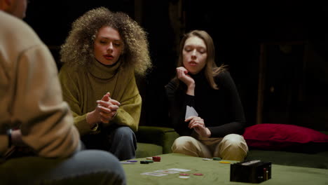 Die-Kamera-Konzentriert-Sich-Auf-Zwei-Frauen,-Die-Mit-Freunden-Auf-Der-Couch-Im-Wohnzimmer-Poker-Spielen