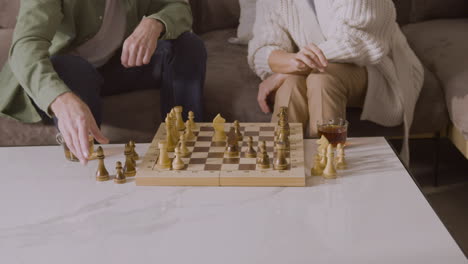 Nahaufnahme-Von-Zwei-Nicht-Erkennbaren-Personen,-Die-Schach-Spielen,-Während-Sie-Zu-Hause-Auf-Dem-Sofa-Sitzen