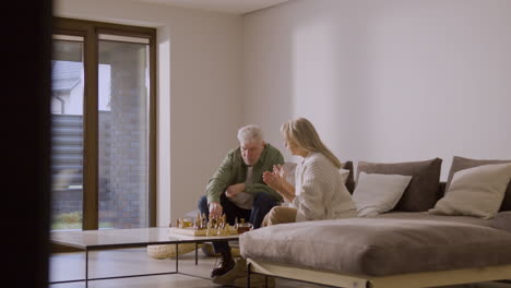 älterer-Mann-Und-Frau-Spielen-Schach,-Während-Sie-Zu-Hause-Auf-Dem-Sofa-Sitzen-3