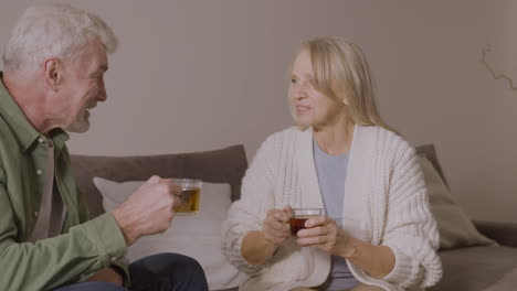 Senior-Man-And-Woman-Drinking-Tea-While-Sitting-On-Sofa-At-Home