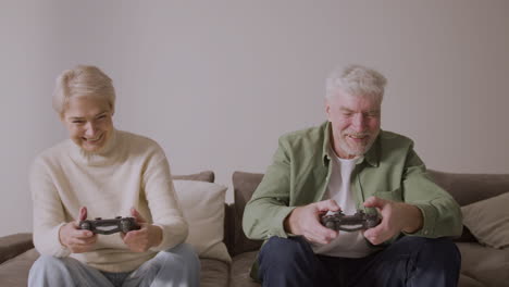 Glücklicher-älterer-Mann-Und-Frau,-Die-Videospiel-Spielen,-Sitzen-Auf-Sofa-Zu-Hause