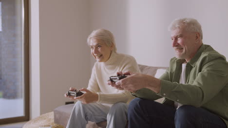 Glücklicher-älterer-Mann-Und-Frau,-Die-Videospiel-Spielen,-Sitzen-Auf-Dem-Sofa-Zu-Hause-1