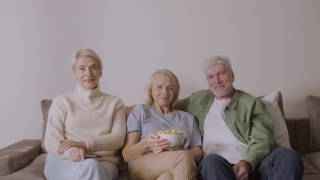 Porträt-Von-Drei-Senioren,-Die-Auf-Dem-Sofa-Sitzen-Und-In-Die-Kamera-Lächeln
