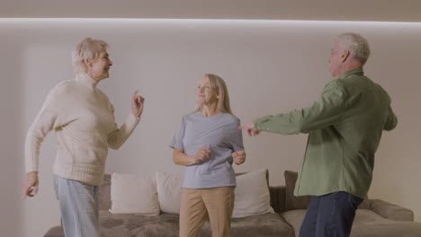 Drei-Glückliche-ältere-Freunde-Tanzen-Zu-Hause-Zusammen
