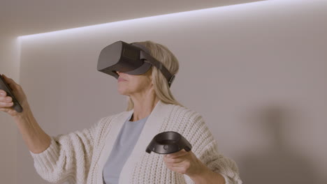 Senior-Woman-Playing-At-Home-With-Virtual-Reality-Goggles-Headset-1