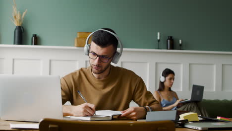 Nahaufnahme-Eines-Studenten-Mit-Kopfhörern-Und-Laptop-Am-Tisch-Sitzen