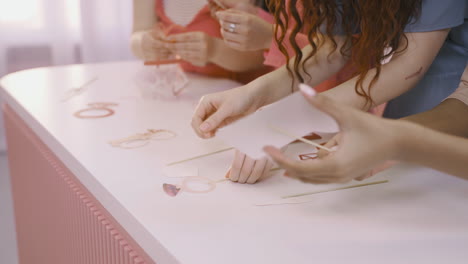 Close-Up-View-Of-Friends's-Hands-Putting-Cardboard-Decorations-On-A-White-Table-For-Bachelorette-Party-Celebration