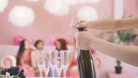 Side-View-Of-Woman's-Hands-Opening-A-Bottle-Of-Champagne-On-The-Table