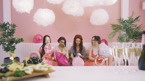Vorderansicht-Von-Vier-Frauen-Mit-Kopfbedeckungen,-Die-Ballons-Werfen,-Die-Auf-Dem-Sofa-Sitzen