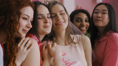 Close-Up-View-Of-Bachelor-Girl-And-Her-Friends-Hugging-And-Wearing-Bride-To-Be-Sashs-And-Headdresses-Posing-At-Camera