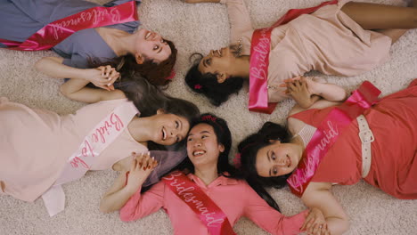 Top-View-Of-Bachelor-Girl-And-Her-Friends-Holding-Hand-Lying-On-The-Carpet