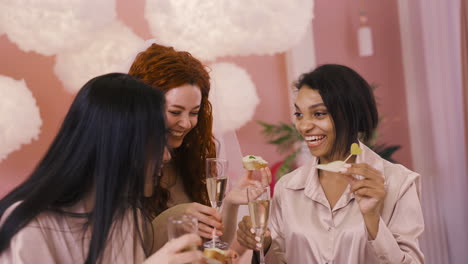 Vorderansicht-Von-Drei-Multiethnischen-Freunden,-Die-Mit-Kristallgläsern-Champagner-Und-Essen-Anstoßen-Und-Junggesellenabschied-Feiern