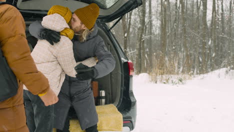 Happy-Friends-Meeting-And-Hugging-On-A-Snowy-Day-Before-Leaving-For-A-Winter-Road-Trip