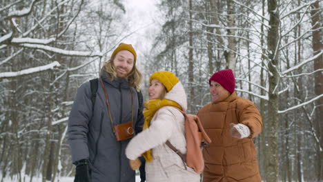 Front-View-Of-Three-Friends-In-Winter-Clothes-Walking-In-A-Winter-Forest