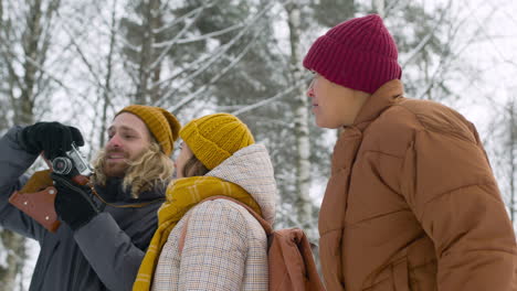 Bottom-View-Of-Three-Friends-In-Winter-Clothes-Talking-About-Something-They-Have-Seen-In-A-Winter-Forest