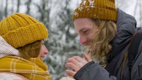 Close-Up-View-Of-A-Man-And-A-Woman-Warming-Their-Hands-In-The-Snowy-Forest-1