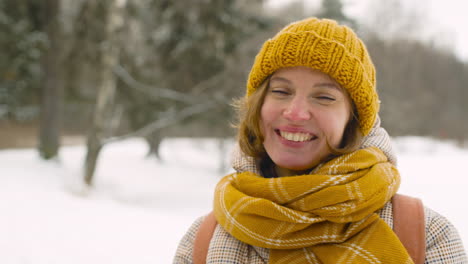 Close-Up-View-Of-A-Smiling-Woman-Looking-Smartphone-And-Around-In-Winter-Forest