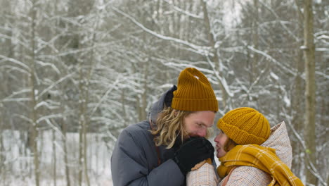 Man-And-A-Woman-Warming-Their-Hands-In-The-Snowy-Forest