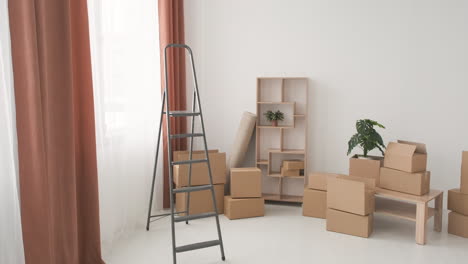 Moving-Boxes-And-Ladder-In-Empty-Room-Of-New-Home