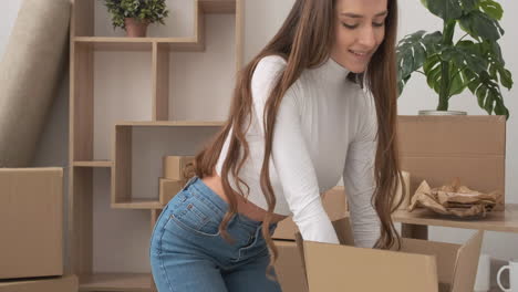 Woman-Sitting-On-Floor-Closing-A-Cardboard-Box-And-Smiling-At-Camera