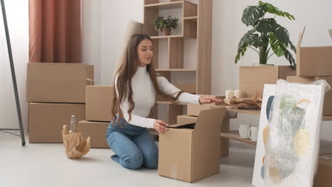 Smiling-Woman-Packing-Bowls-Into-Cardboard-Box-For-Moving