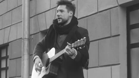 Schwarz-Weiß-Ansicht-Eines-Mannes-Im-Mantel,-Der-Auf-Der-Straße-Singt-Und-Gitarre-Spielt