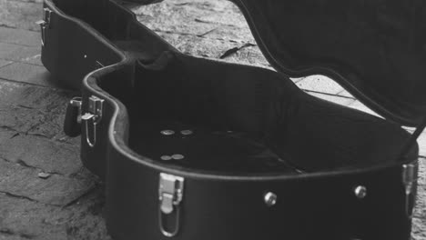 Black-And-White-And-Close-Up-View-Of-Coins-Falling-Into-A-Guitar-Case