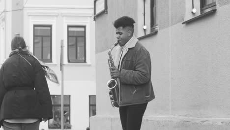 Black-And-White-View-Of-A-Sax-Case-On-The-Floor-And-A-Man-In-Jacket-Playing-Sax-In-The-Street