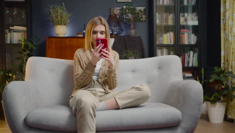 Junge-Frau,-Die-Smartphone-Verwendet,-Während-Sie-Zu-Hause-Auf-Einer-Couch-Sitzt