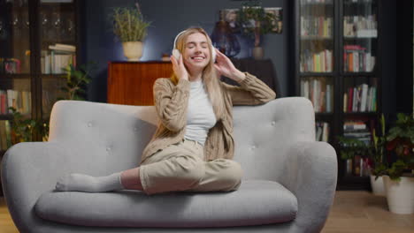 Happy-Young-Woman,-With-Closed-Eyes,-Listening-Music-In-Wireless-Headphones-While-Sitting-On-A-Couch-At-Home