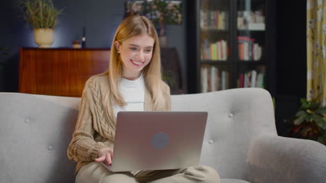 Beautiful-Young-Woman-Chatting-On-Laptop-Computer-While-Sitting-On-Couch-At-Home
