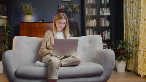 Schöne-Junge-Frau-Mit-Laptop-Computer,-Während-Sie-Zu-Hause-Auf-Der-Couch-Sitzt