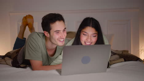 Close-Up-View-Of-A-Couple-Watching-Interesting-Movie-On-Laptop-Lying-In-Bed-At-Home