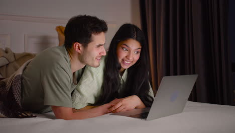 Close-Up-View-Of-A-Couple-Watching-Interesting-Movie-On-Laptop-Lying-In-Bed-At-Home-1