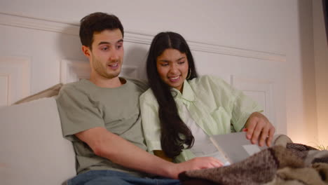 Couple-Watching-Unpleasant-Movie-Scene-On-Laptop-Sitting-On-Bed-At-Home