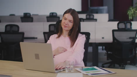 Smiling-Pregnant-Woman-Working-In-The-Office-And-Caressing-Her-Belly