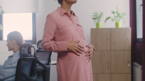 Close-Up-Of-Happy-Pregnant-Woman-With-Wirless-Earphones-Listening-Music-And-Dancing-In-The-Office