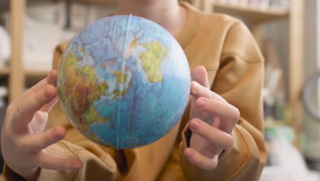 Close-Up-View-Of-Unrecognizable-Kid-Playing-With-A-Globe-In-A-Craft-Workshop