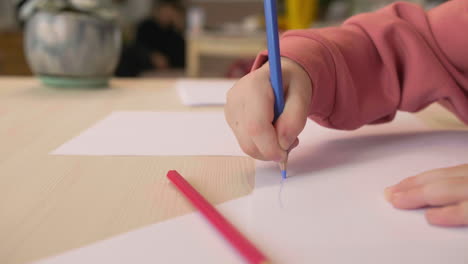 Close-Up-View-Of-Unrecognizable-Little-Girl-Drawing-On-A-Paper-Sitting-At-A-Table-In-A-Craft-Workshop