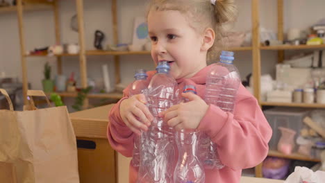 Little-Blonde-Girl-Holding-Plastic-Bottles-In-A-Craft-Workshop