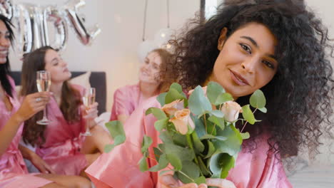 Muslimische-Frau-Mit-Blumenstrauß,-Rosafarbenem-Nachthemd-Aus-Seide,-Lächelnd-Und-Blick-In-Die-Kamera-1