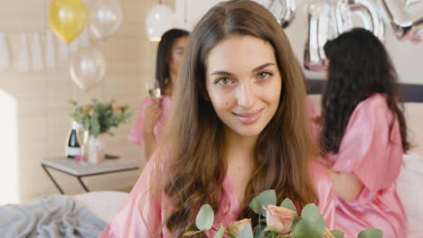 Brunette-Woman-Holding-Bouquet,-Wearing-Pink-Silk-Nightdresses,-Smiling-And-Looking-At-Camera