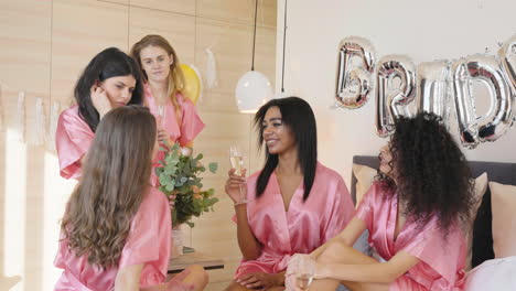 Gruppe-Multiethnischer-Freundinnen-In-Rosa-Seidennachthemden,-Die-Sich-Unterhalten,-Während-Sie-Champagnergläser-Halten-2