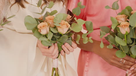 Camera-Focuses-On-Hands-Of-Female-Friends-And-Bride-Holding-Bouquets-1