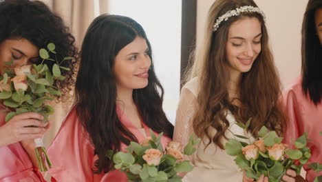 Gruppe-Multiethnischer-Freundinnen-Und-Braut,-Die-Seidenrosa-Und-Weiße-Nachtkleider-Tragen-Und-Blumensträuße-Halten