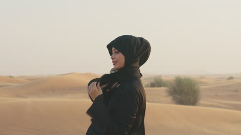 Portrait-Of-A-Beautiful-Muslim-Woman-With-Hijab-Walking-In-A-Windy-Desert-And-Looking-At-Camera-3