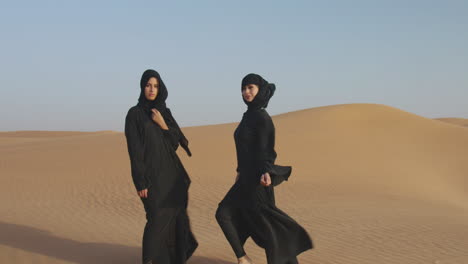 Zoom-En-La-Toma-De-Dos-Hermosas-Mujeres-Musulmanas-En-Hiyab-Posando-En-Un-Desierto-Ventoso-Y-Mirando-A-La-Cámara