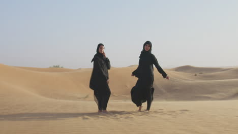 Two-Beautiful-Muslim-Women-In-Hijab-Standing-In-A-Windy-Desert-And-Smiling-At-Camera-3