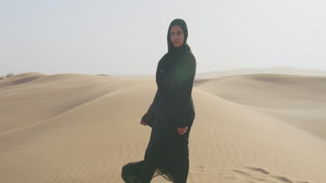 Vergrößern-Sie-Die-Aufnahme-Einer-Muslimischen-Frau-Mit-Hijab,-Die-In-Einer-Windigen-Wüste-In-Die-Kamera-Schaut